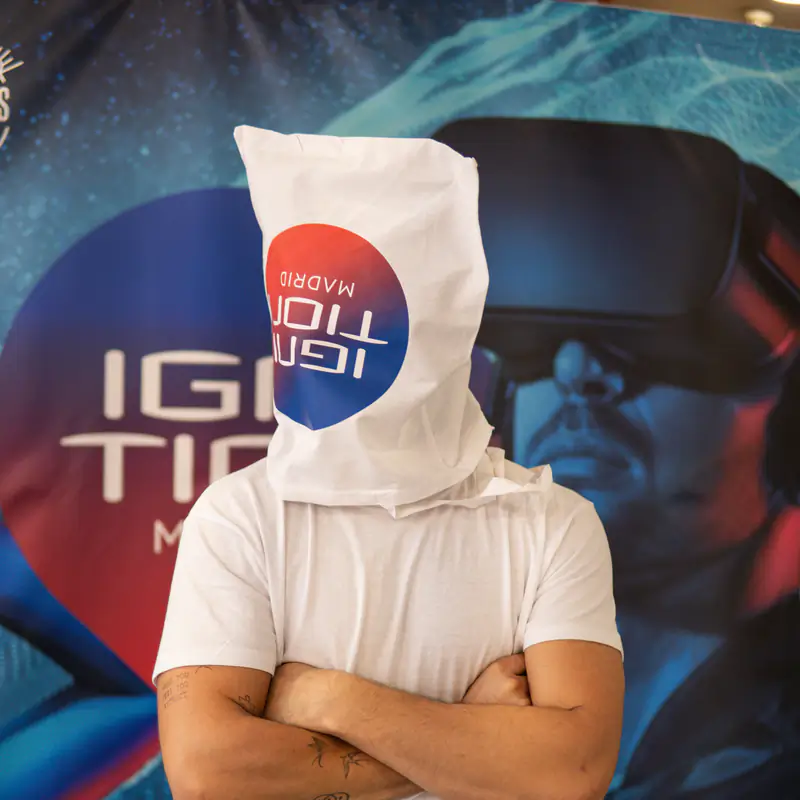 Un asistente posa en broma en el photocall de Ignition Madrid 2025 con una bolsa del evento en la cabeza.